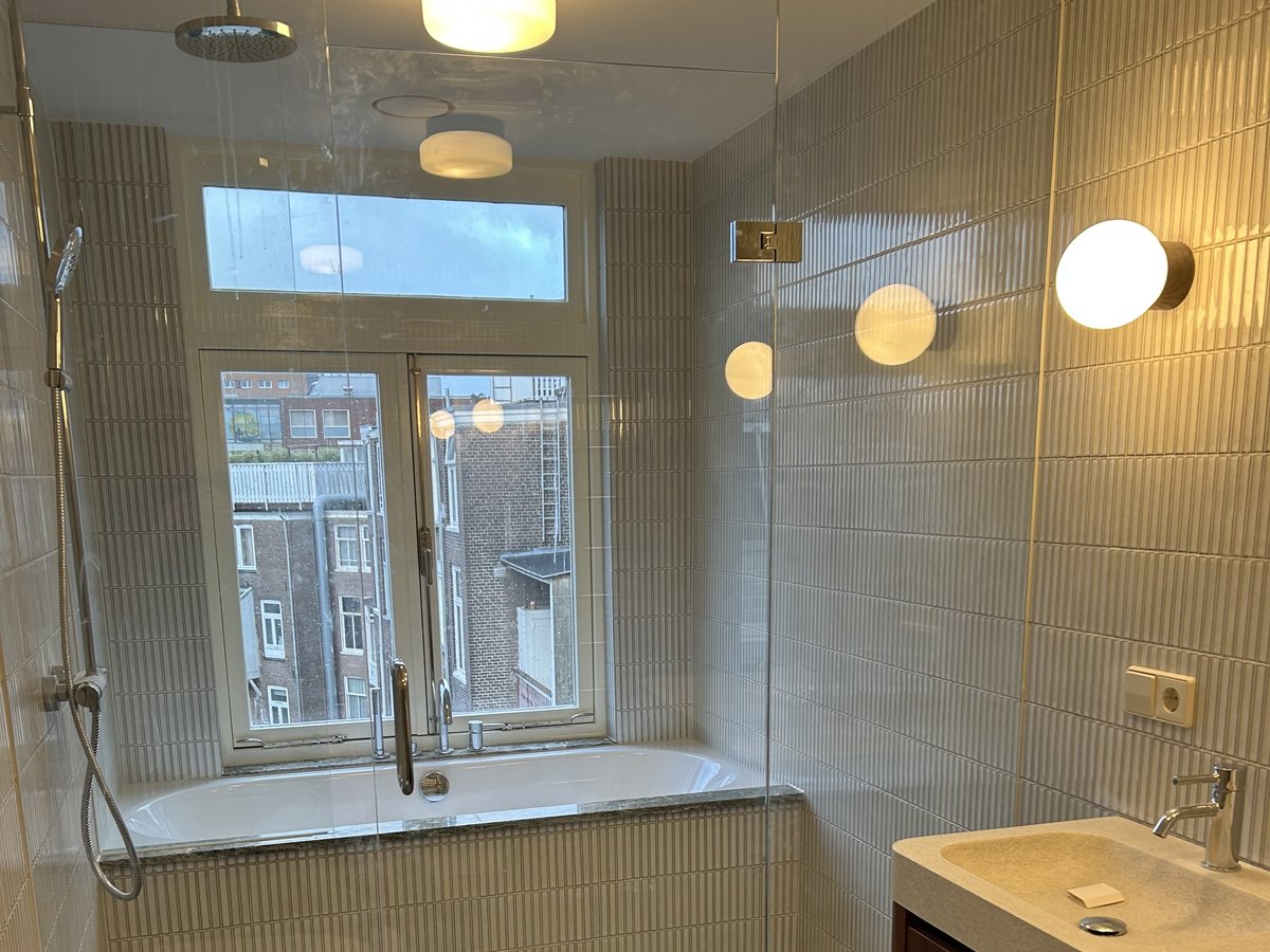 Gerenoveerde badkamer met bad, inloopdouche en afgemonteerde verlichting