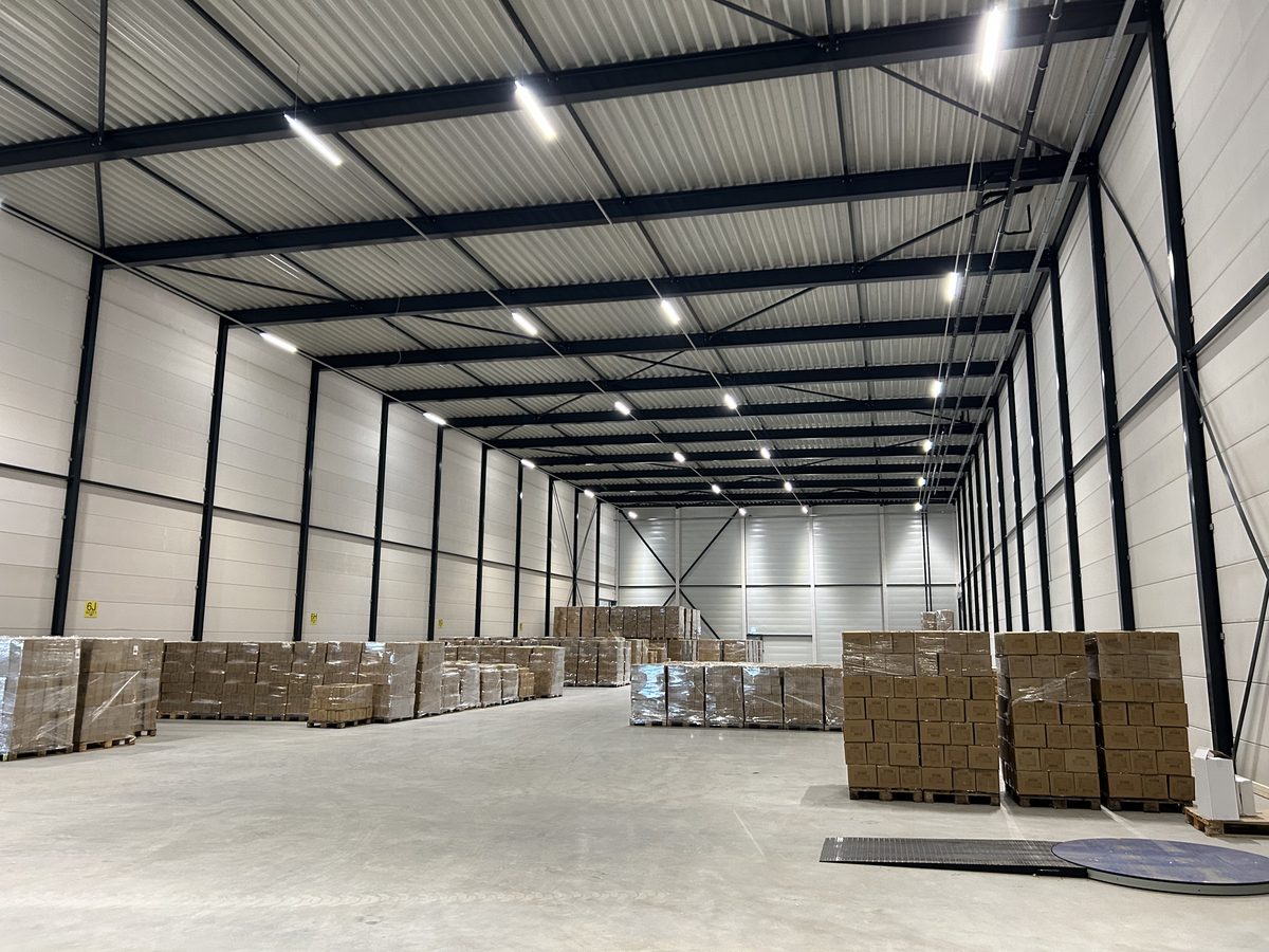 Bedrijfshal in gebruik, met door WLS Techniek aangelegde verlichting boven de opslag